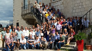 Gruppenfoto mit ungefähr 100 Personen, die vor einem weißen Haus stehen. Die Hälfte der Personen steht auf einer Treppe des Hauses.