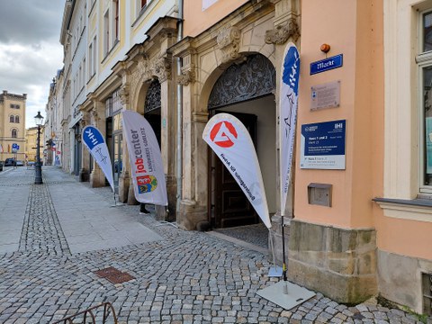 Fahnen der IHK Dresden und des Jobcenters Görlitz laden vor dem Haupteingang des IHI Zittau zur Arbeitgeberkonferenz ein