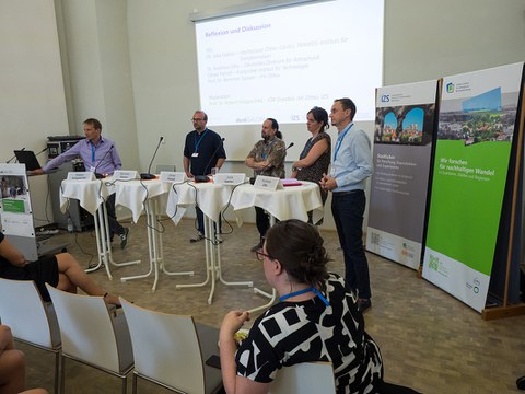 Podiumsdiskussion im Denksalon 2024. Die Vortragenden stehen an Stehtischen.