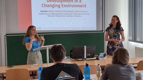 Mariia Foschchij von der TU Kharkiv während ihres Vortrags. Hinter ihr ist eine Power-Point-Präsentation zu sehen, im Vordergrund Studierende, die zuhören.