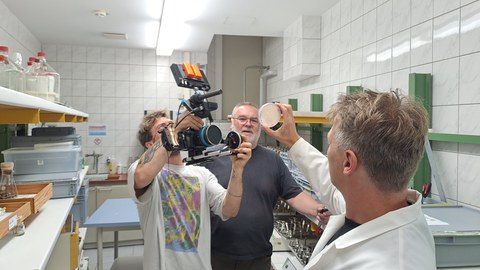 IHI-Mitarbeiter Alexander Karich hält im Labor eine Pilzprobe in die Kamera des ARD-Teams