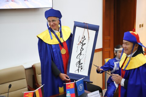 Prof. Karsten Wesche bei der Verleihung der Ehrendoktorwürde der Mongolischen Nationaluniversität. Er ist im feierlichen Ornat mit einer Schriftrolle zu sehen.