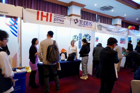 Messestand des IHI Zittau und der TUDIAS bei der 1. Sächsisch-Mongolischen Bildungsmesse in Ulaanbataar. Zahlreiche Besucherinnen und Besucher im Gespräch mit Frau Khurelpurev vom IHI Zittau.