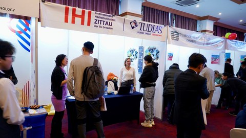 Messestand des IHI Zittau und der TUDIAS bei der 1. Sächsisch-Mongolischen Bildungsmesse in Ulaanbataar. Zahlreiche Besucherinnen und Besucher im Gespräch mit Frau Khurelpurev vom IHI Zittau.