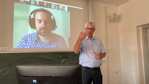 Herr Professor Thorsten Claus, Direktor des IHI Zittau, bei seinem Vortrag im Rahmen der Tagung "Zukunft Alter". Im Bildhintergrund ist die Videokonferenz zu erkennen, die zugleich läuft.