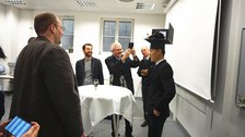 Hao Zhang auf seiner Promotionsfeier mit Hut und Kollegen im Hintergrung