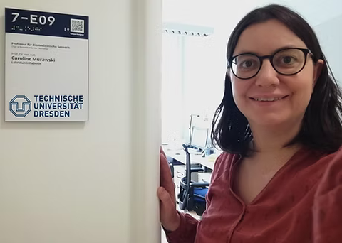 Frau Caroline Murawski mit einem strahlenden lächeln vor Ihrem neuen Büro an der Technischen Universität Dresden.