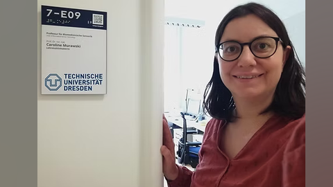 Frau Caroline Murawski mit einem strahlenden lächeln vor Ihrem neuen Büro an der Technischen Universität Dresden.