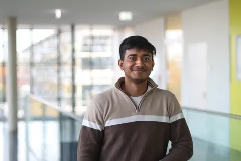 Fardeen smiles and wears a brown-beige sweater with a zipper.