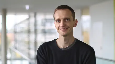 Felix Schmieder lächelt in die Kamera. Er trägt einen schwarzen Pullover.