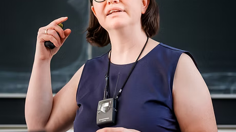 Frau Prof. Caroline Murawski gestikuliert beim Beantworten einer Fragestellung vor der Tafel.