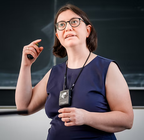 Frau Prof. Caroline Murawski gestikuliert beim Beantworten einer Fragestellung vor der Tafel.
