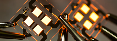 Four square, orange glowing areas situated on a larger glass substrate, including electrical conductor tracks and connected crocodile clips.