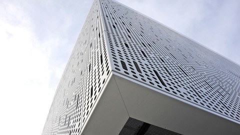 Die Eckfassade des Werner-Hartmann-Bau aus Froschperspektive. Die perforation der Fassade ist deutet eine Mikroelektronik-Leiterplattenstruktur an.