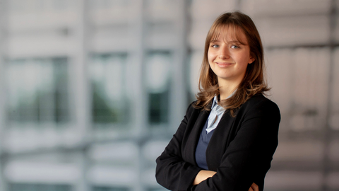 Amy Fritz smiles into the camera. She wears buisness cloths with a black blazer, blue pullover and a light blue striped shirt.