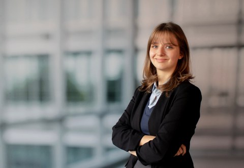 Amy Fritz smiles into the camera. She wears buisness cloths with a black blazer, blue pullover and a light blue striped shirt.