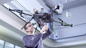 Ein Wissenschaftler der Nachwuchsforschergruppe ADFEX zeigt einen Flugroboter.