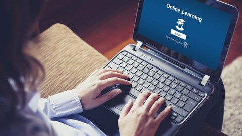 Das Foto zeigt eine Person mit einem Laptop auf dem Schoß. Darauf erkennt man die Seite einer Online-Lernplattform.