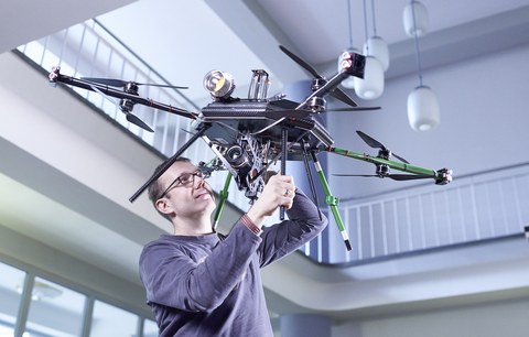 Bild: ein Man hält eine Drohne über dem Kopf