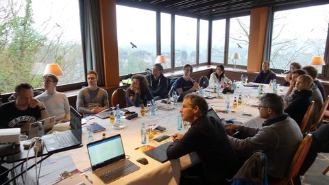 Mehrere Personen sitzen an einem Konferenztisch und diskutieren.