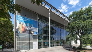 Frontansicht des Hörsaalzentrums der TU Dresden. Am Gebäude Hängt ein Poster mit der Aufschrift: "Wissen Schafft Exzellenz".