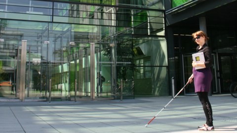 Blinde Studentin vor dem Eingang der Fakultät
