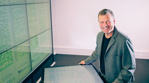 Prof. Wolfgang Lehner am Multitouch Tisch vor dem Großdisplay