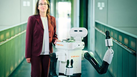 Frau Prof. Diana Göhringer mit den Roboter Tiago im Flur der Fakultät Informatik