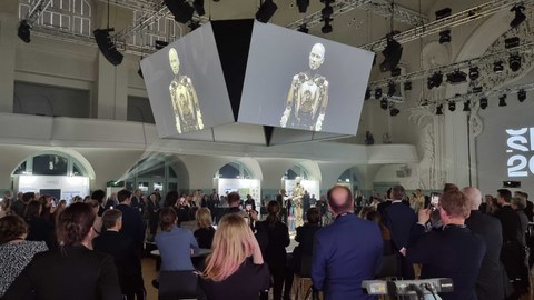 Auftaktveranstaltung zur "SPIN 2023" am 3. Februar in Leipzig, Messehalle voller Menschen mit Blick auf Roboter Dame Omega