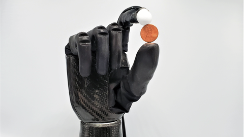 Roboterhand mit Kugel zwischen Zeigefinger und Daumen
