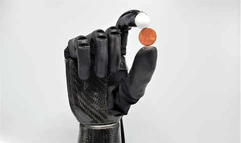 Roboterhand mit Kugel zwischen Zeigefinger und Daumen