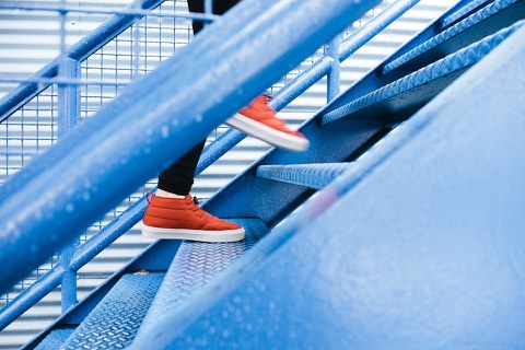 Füße mit roten Turnschuhen laufen eine Stahltreppe hinauf