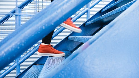 Füße mit roten Turnschuhen laufen eine Stahltreppe hinauf