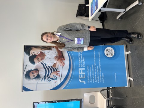 Wissenschaftlerin steht vor Schild der Konferenz