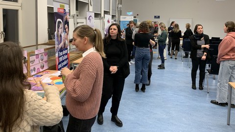 Weibliche Personen an Ausstellungsständen und in Gesprächen