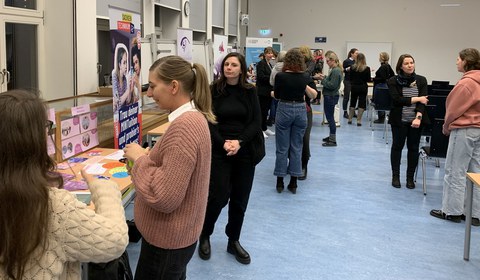 Weibliche Personen an Ausstellungsständen und in Gesprächen