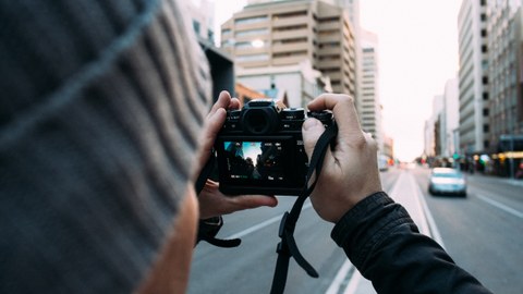Foto eines Mannes, der mit seiner Kamera ein Foto in einer Großstadt macht.