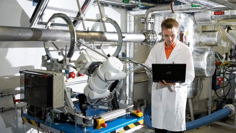 Photo of an employee in front of a test facility for the investigation of heat transfer in heat exchangers  