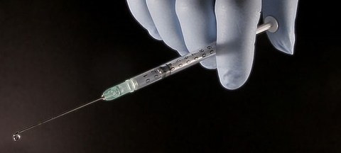 Depiction of a syringe in a gloved hand.