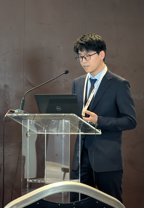 Qiu Lu am Rednerpult, den Blick auf seine Notizen gerichtet.