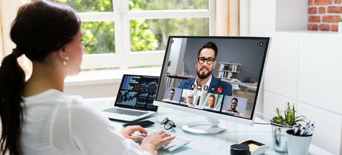 Foto einer Person an ihrem Schreibtisch, die mit 5 Kollegen ein Online-Meeting hält.