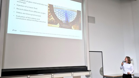 Valentin Scheffel während seines Vortrags, im Hörsaal stehend und auf die Präsentation zeigend.