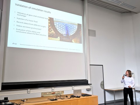 Valentin Scheffel während seines Vortrags, im Hörsaal stehend und auf die Präsentation zeigend.