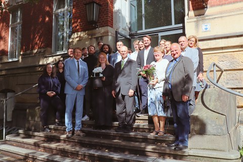 Die Gruppe der Gäste und Kollegen der Promovierenden stehen auf der Treppe eines Gebäudes für ein Gruppenfoto zusammen.