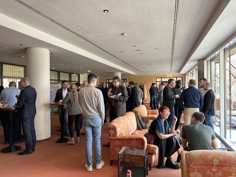 Menschen stehen locker beieinander, unterhalten sich in den Pausen im Foyer.
