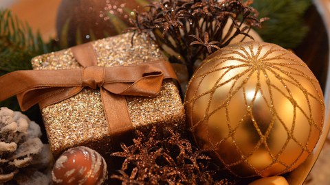 Weihnachtliches Motiv mit goldenem Schein, Geschenke und Weihnachtskugeln, Tannenzapfen und Glitterband.