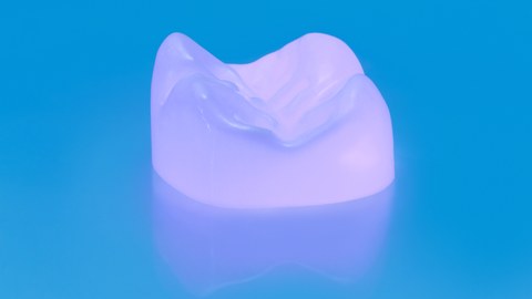 Das Bild zeigt eine künstliche Zahnkrone aus UV-aktiver Keramik.