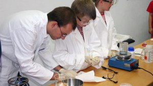 A scientist and some children, all clothed in white lab coats, are carrying out a chemical experiment during the Lange Nacht der Wissenschaft.