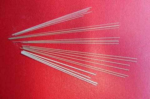 Piezoceramic fibres of various thickness fan out on a red surface.