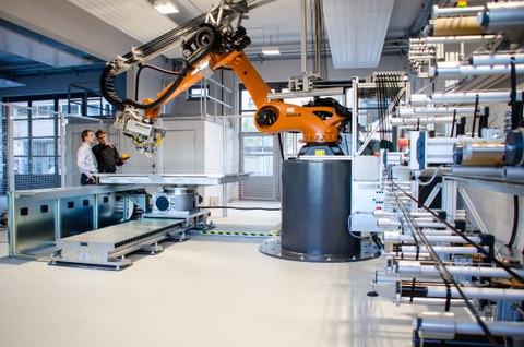 Zwei Wissenschaftler des Instituts für Leichtbau und Kunststofftechnik arbeiten an einer Tapelegeanlage..